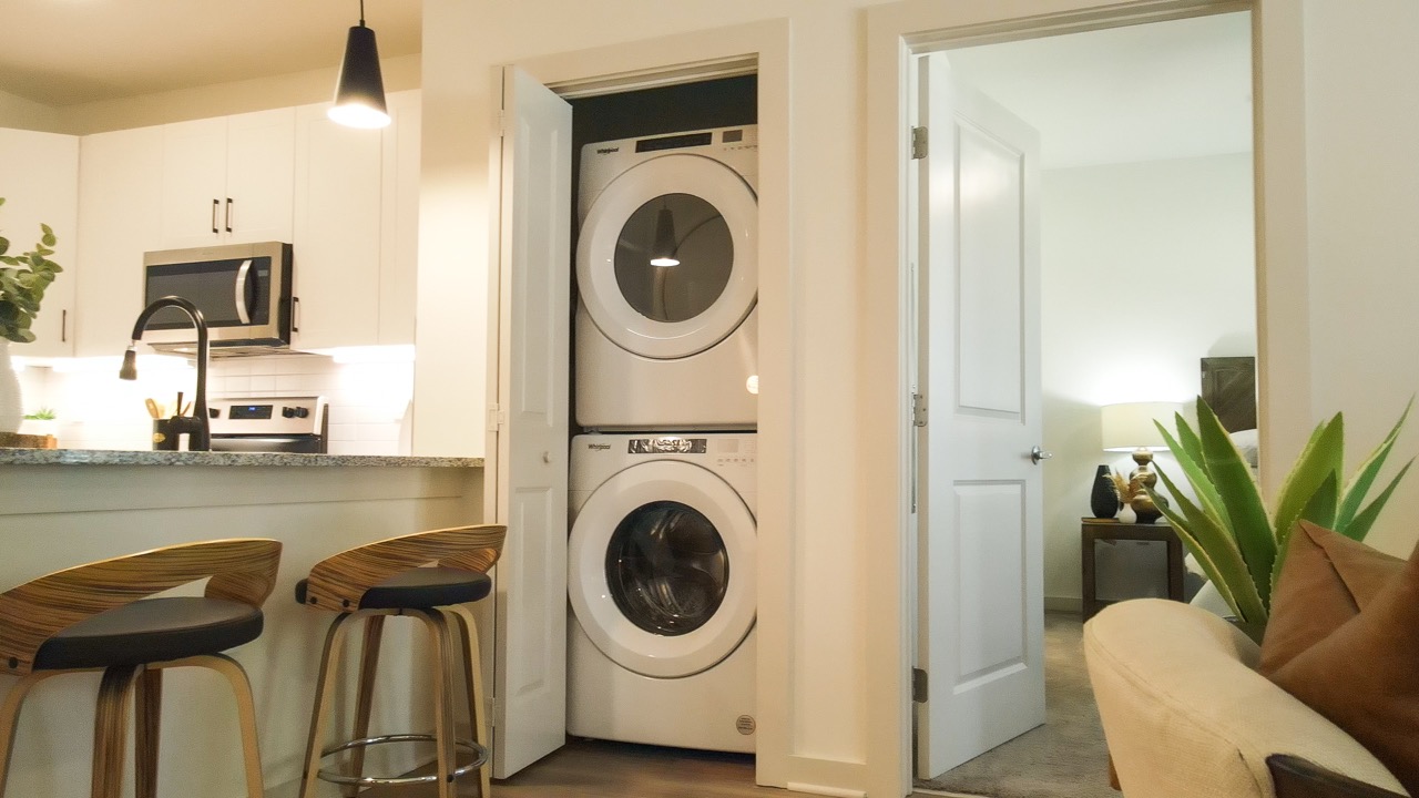 Interior of a Sage North apartment featuring a modern kitchen, stainless steel appliances, and an in-unit washer and dryer for ultimate convenience.