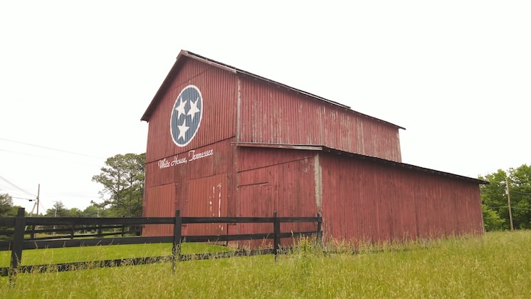 An iconic red barn, painted like a Tennessee State Flag. Just under the flag log, the words White House, Tennessee are written out.