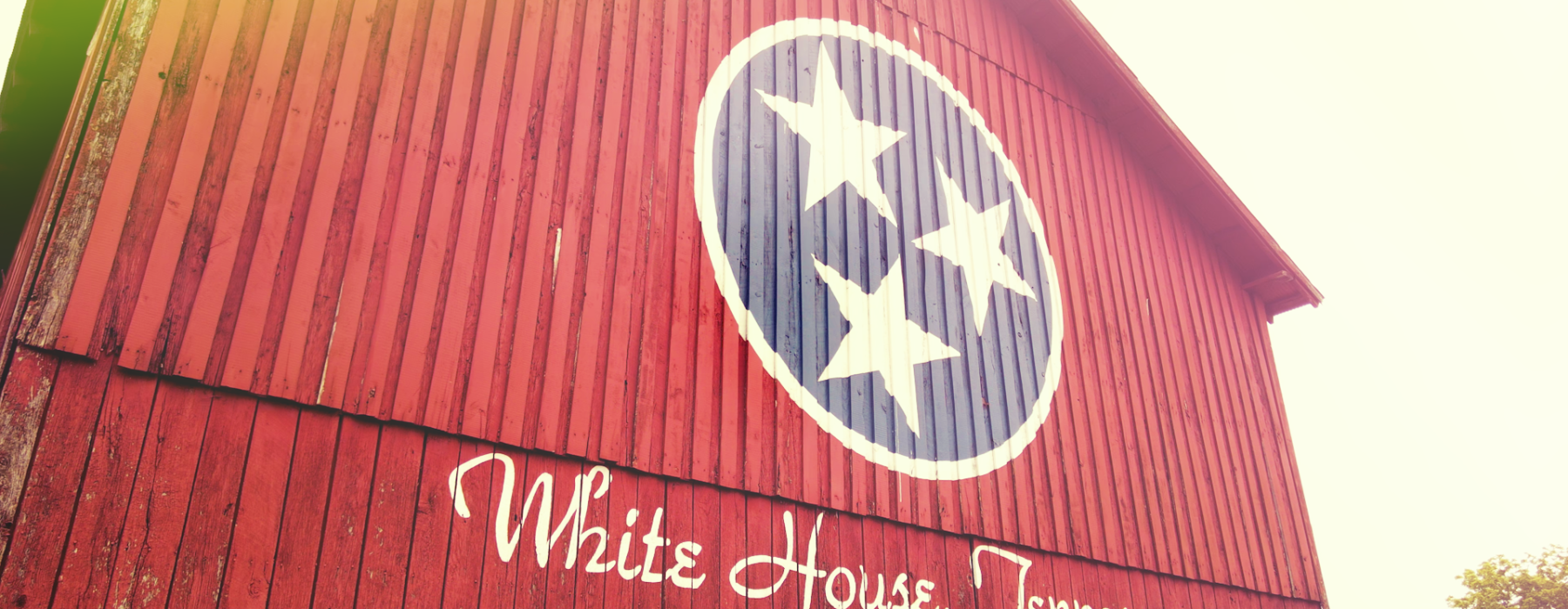 Barn painted with Tennessee Flac colors and symybols, with writing that reads "White House, Tennessee" 