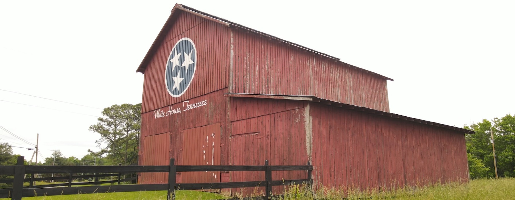 An iconic red barn, painted like a Tennessee State Flag. Just under the flag log, the words White House, Tennessee are written out.