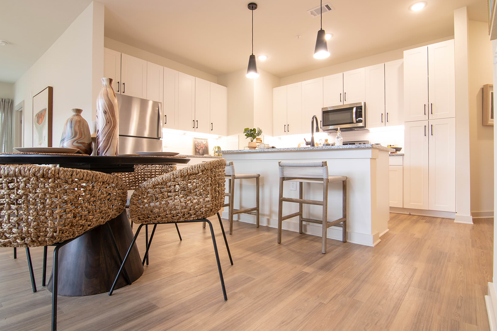 Modern Kitchen with Full-Size 42'' Cabinets & Open-Concept Design at Sage North Spacious kitchen at Sage North apartments in White House, TN, featuring full-size 42-inch cabinets, granite countertops, stainless steel appliances, an undermount sink, pendant lighting, and an open-concept layout with a dining area.